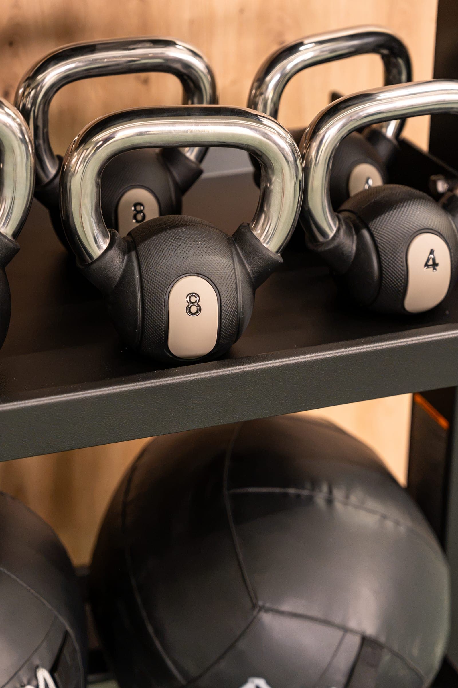 Kettlebells and medicine balls on a rack in the MONA&CO gym